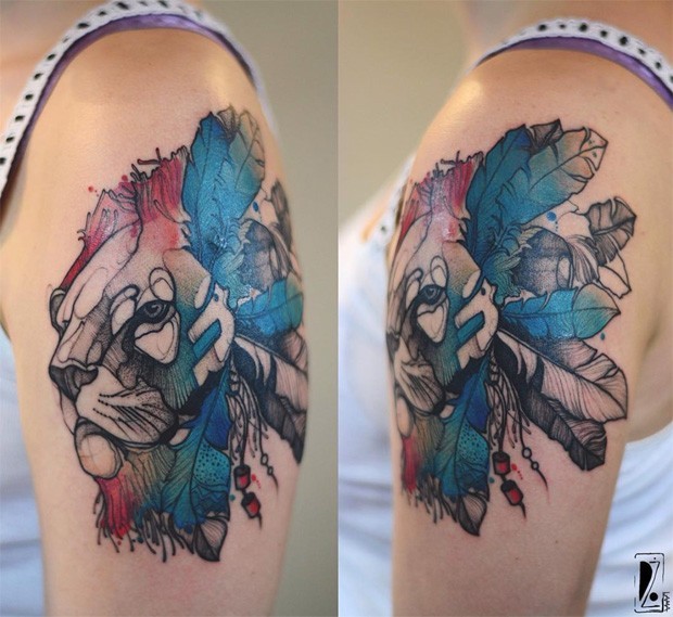 Sketch style colored by Joanna Swirska upper arm tattoo of lion with feather