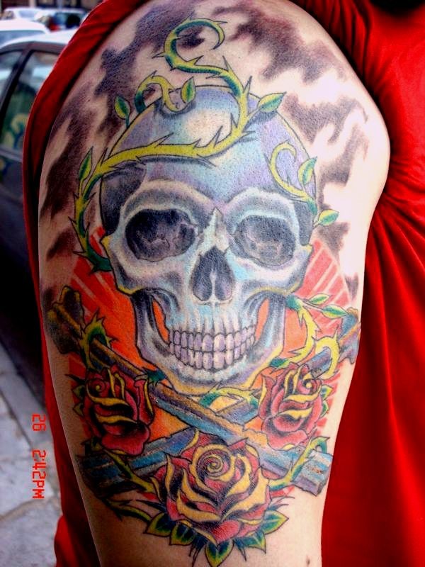 Tatuaggio colorato sul deltoide il teschio & le rose & le spade