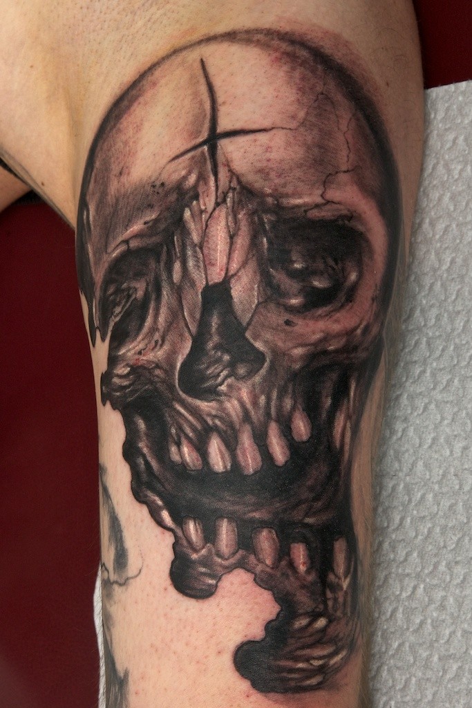 Tatuaje en el brazo, cráneo con la grieta en la frente