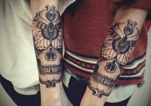 Tatuaggio su due bracci i teschi stilizzati