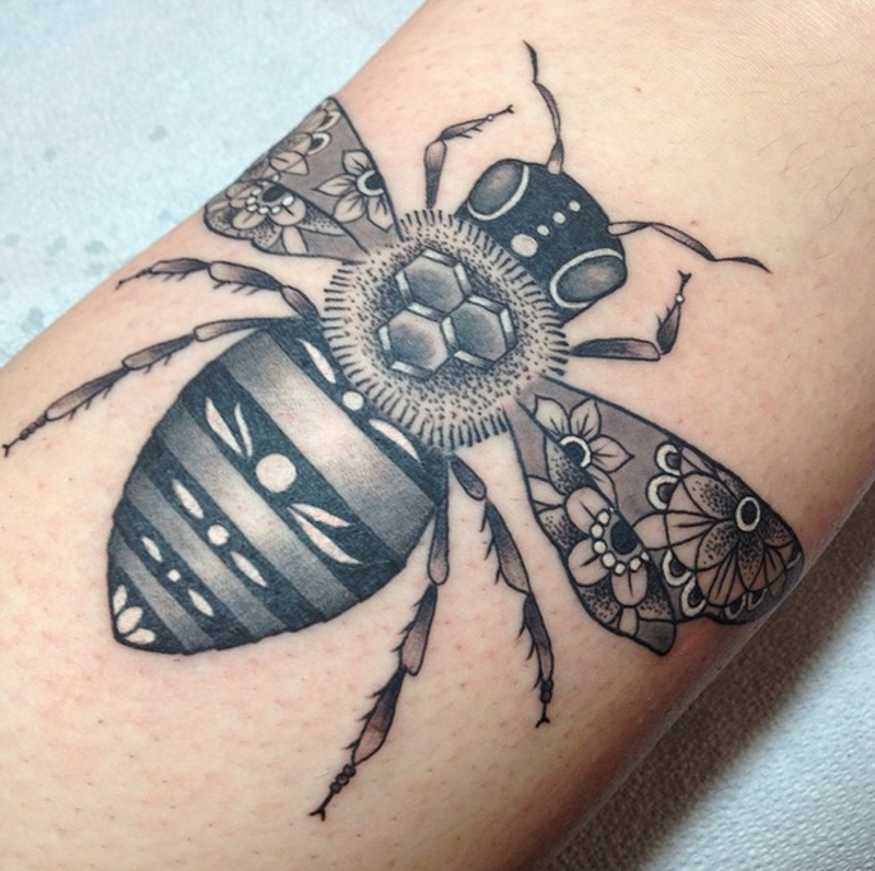 Small black and white bee tattoo stylized with various ornamnets