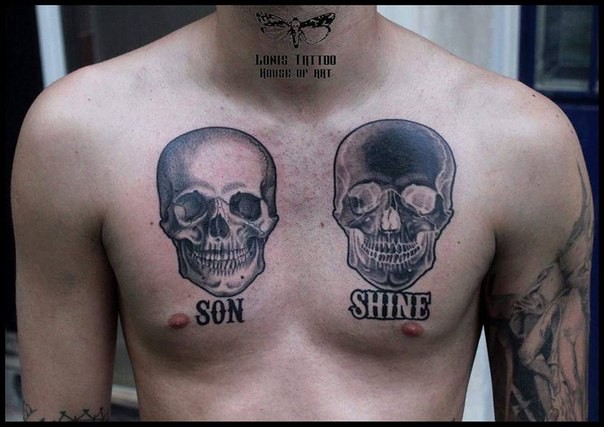 Small black and white chest tattoo of human skulls and lettering
