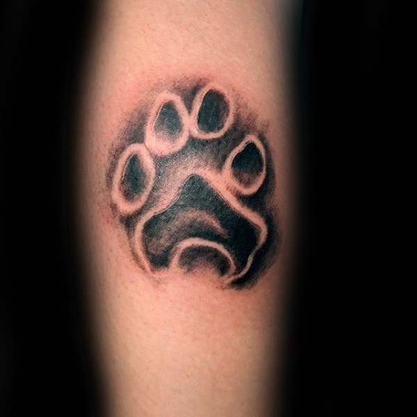 Small black ink arm tattoo of animal paw print