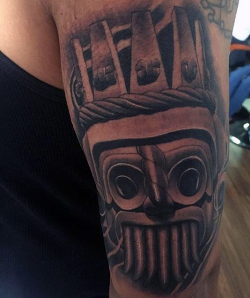 Small black ink detailed tribal statue tattoo on shoulder
