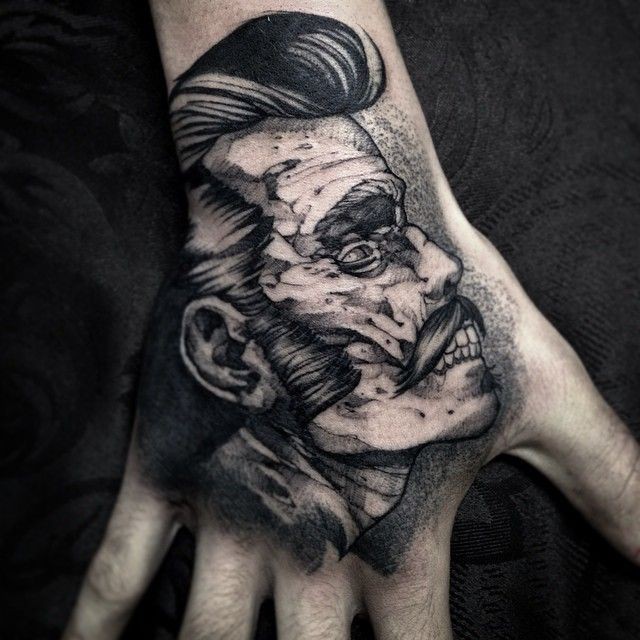 Small black ink engraving style monster zombie face tattoo on hand