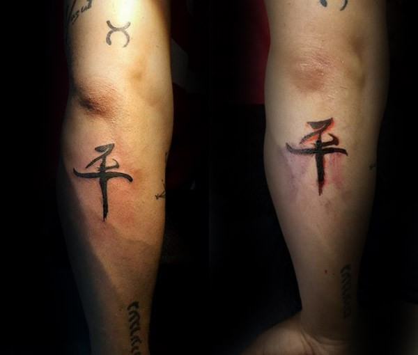 Small black ink forearm tattoo of mystical cross