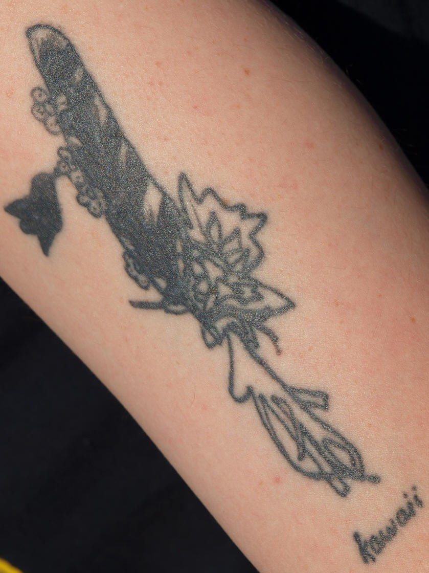 Tatuaje negro de colibrí en una flor exótica
