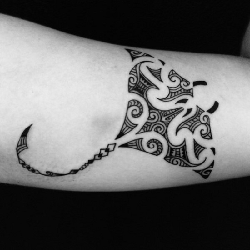 Small black ink slope tattoo on forearm stylized with tribal ornaments