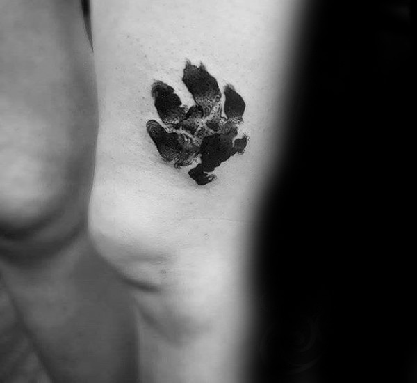 Small black ink thigh tattoo of animal paw print