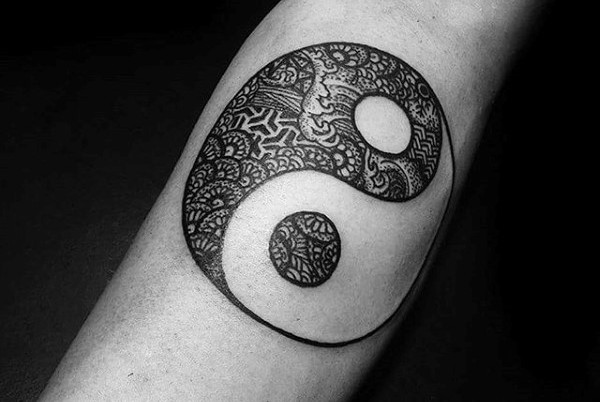 Small black ink Yin Yang symbol tattoo stylized with ornamental flowers