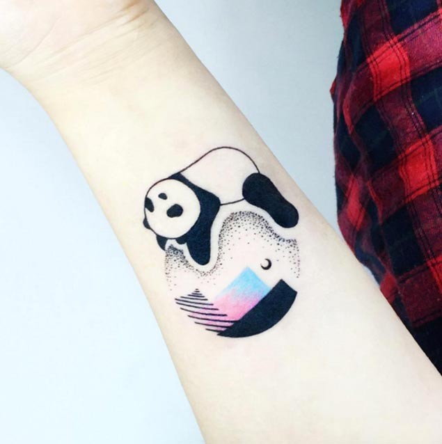 Small cartoon style colored forearm tattoo of sleeping panda on planet