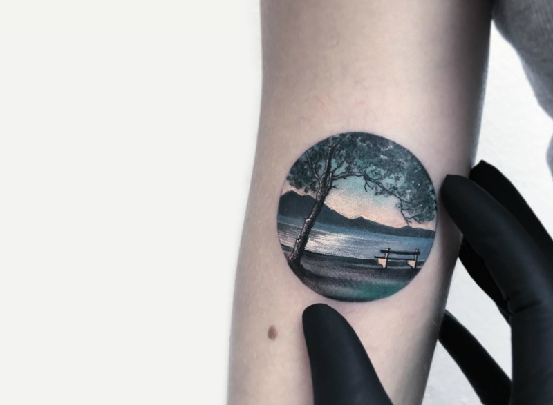 Small circle shaped arm tattoo of big island with tree