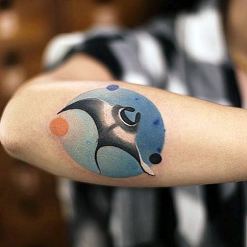 Small circle shaped colored tattoo on forearm stylized with swimming ray