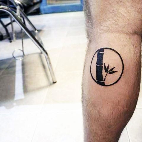 Small circle shaped leg bone tattoo stylized with bamboo
