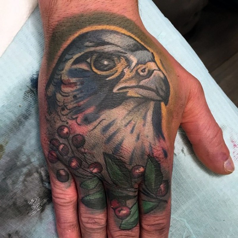 Small colored hand tattoo of eagle head and berries