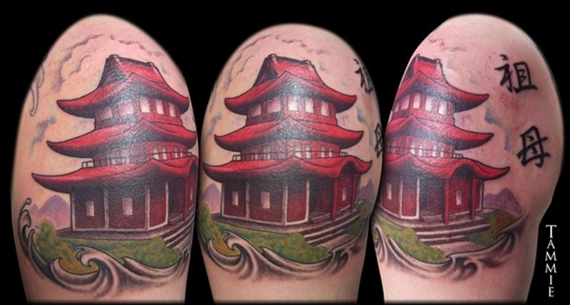 Small cute looking red temple tattoo on shoulder with lettering