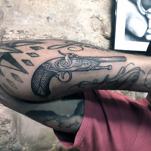 Small detailed black ink engraving style forearm tattoo of antic pistol