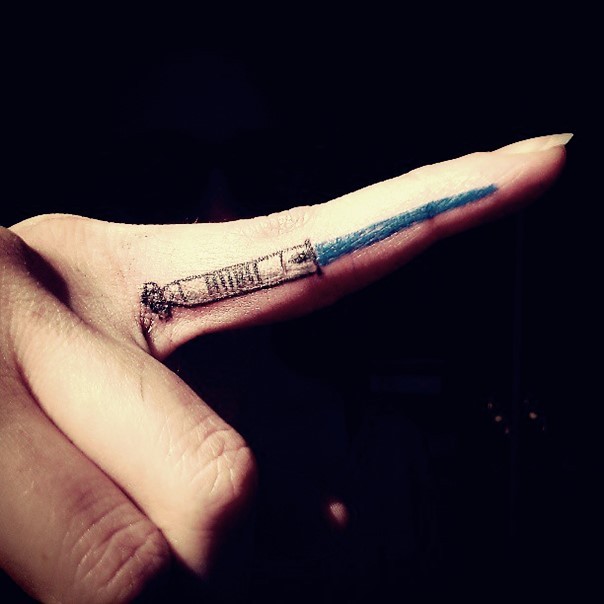 Small detailed blue colored light saber tattoo on point finger