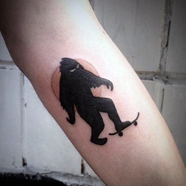 Small funny looking colored forearm tattoo of Yeti with skateboard