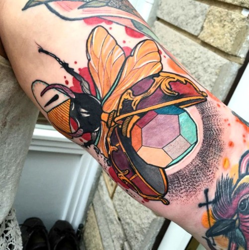 Small illustrative style colored arm tattoo of marvelous bug with stone