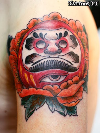 Small illustrative style shoulder tattoo of daruma doll with rose and creepy eye
