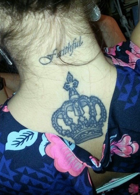 corona e piccola scrittura sulla nuca tatuaggio su schiena superiore