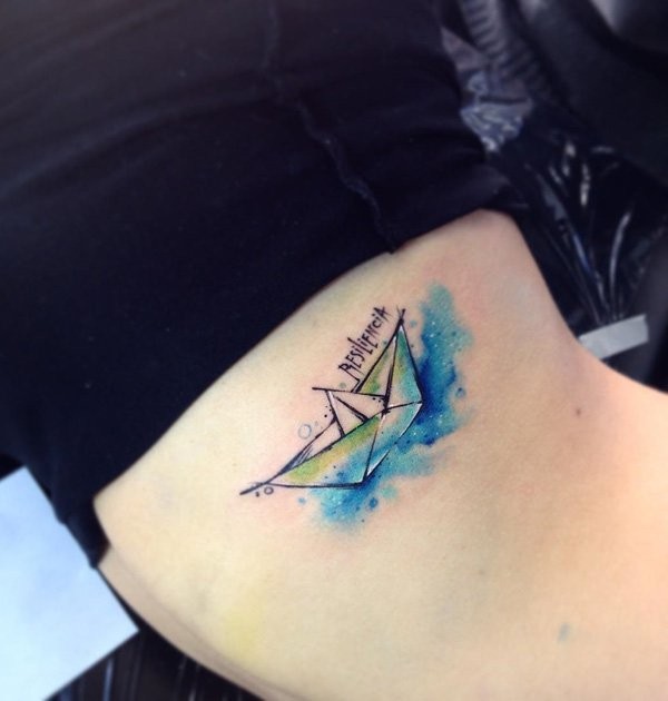 Small watercolor style biceps tattoo of paper ship with lettering