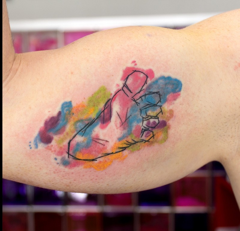 Kleines im Aquarell Stil gefärbtes Bizeps Tattoo mit Baby Fußabdruck