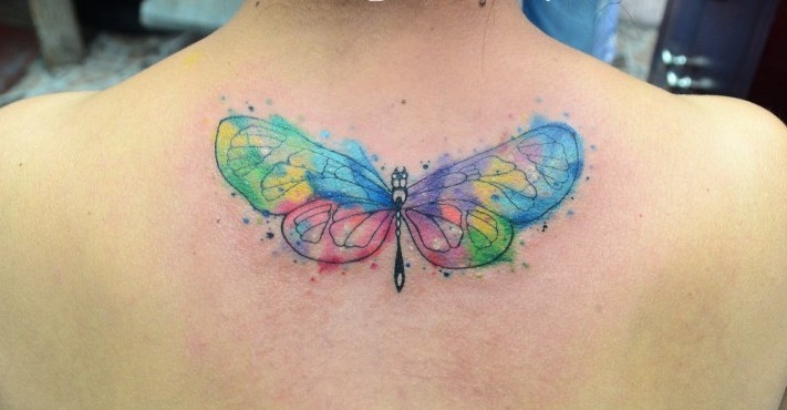 Small watercolor style colored butterfly tattoo on upper back