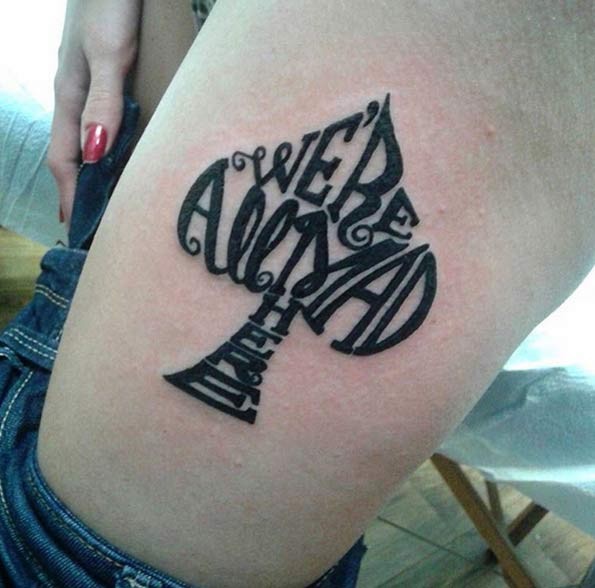 Spades symbol shaped dark black ink lettering tattoo on thigh