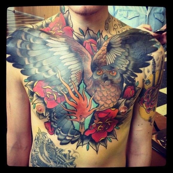 Spectacular multicolored massive owl tattoo on chest combined with rose flowers and candle