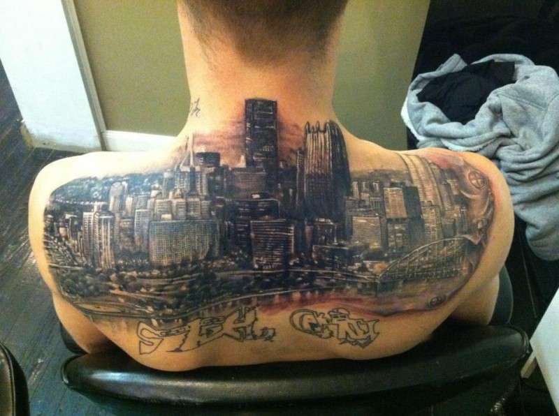 Spectacular multicolored upper back tattoo of big city sights and lettering