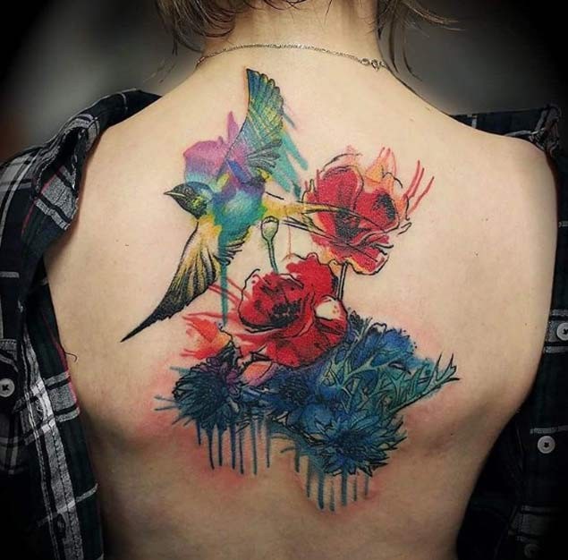 Spectacular watercolor style painted upper back tattoo of bird with flowers
