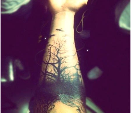 Tatuaje en el antebrazo, árboles sombríos y aves