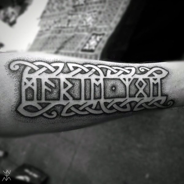 Stippling style black ink ancient lettering tattoo on arm