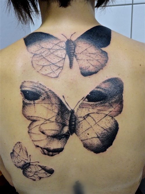 Stippling style black ink back tattoo of butterflies stylized with human eyes