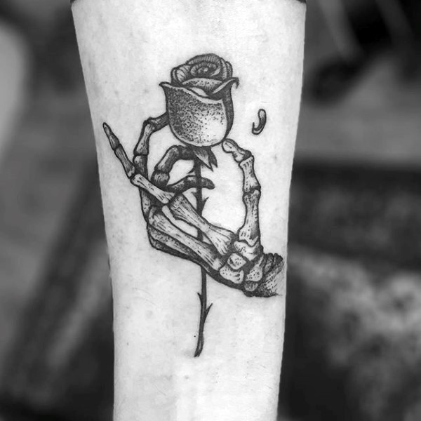 Stippling style black ink tattoo of skeleton hand holding rose
