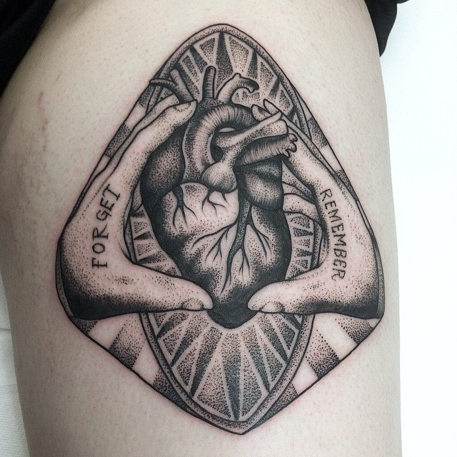 Stippling style black ink thigh tattoo of hands holding human heart and lettering