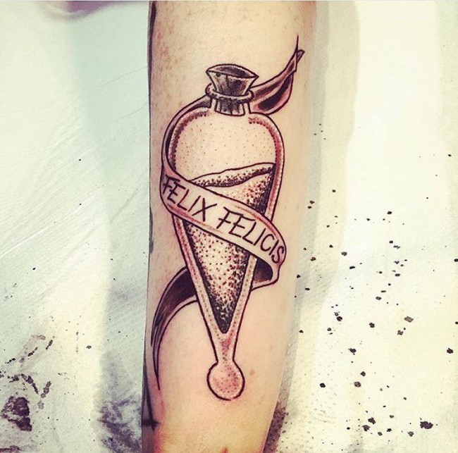 Stippling style colored arm tattoo of magical potion with lettering