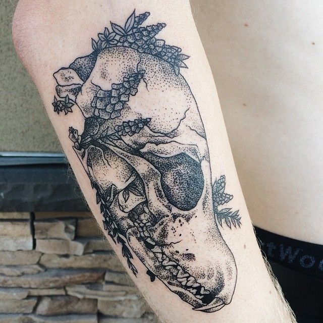 Stippling style colored forearm tattoo of animal skull with leaves
