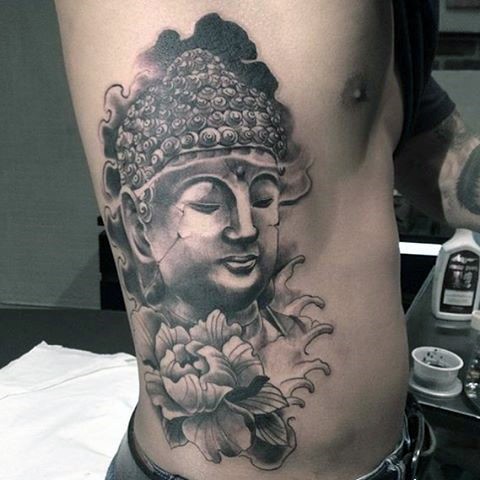 Stonework style black ink side tattoo of Buddha statue and large flower