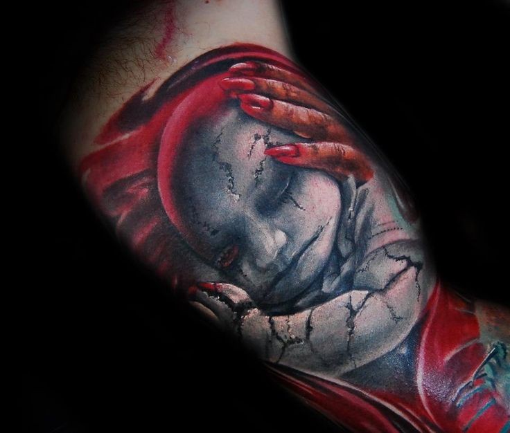 Stonework style colored biceps tattoo of corrupted baby doll