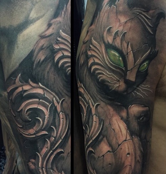 Stonework style detailed looking shoulder tattoo of cat statue with green eyes