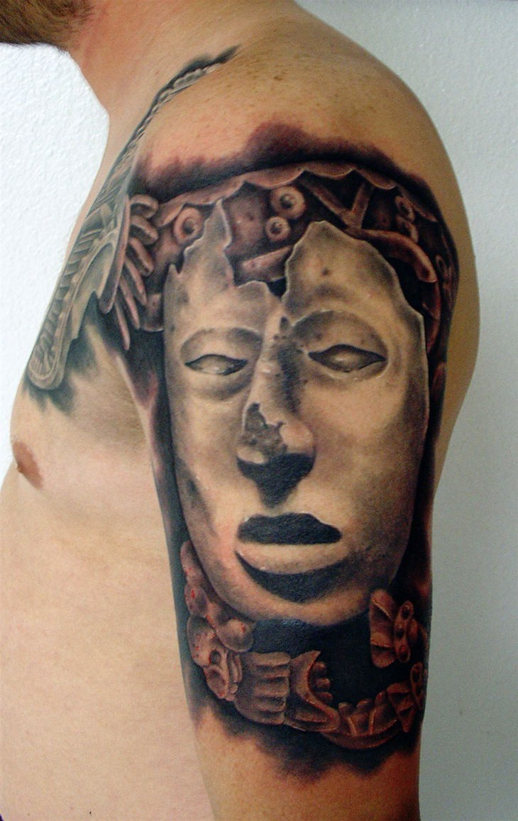 Stonework style shoulder tattoo of cool looking mask