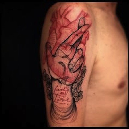 Strange looking human hand with lettering and heart tattoo on shoulder