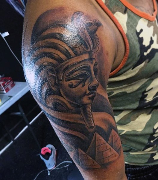 Stunning black ink big Pharaoh statue tattoo on shoulder combined with pyramids