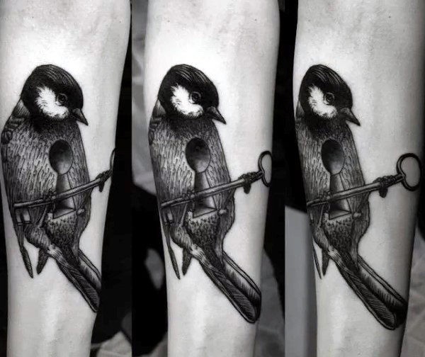 Impresionante tatuaje de antebrazo de tinta negra de pájaro combinado con llave y ojo de cerradura