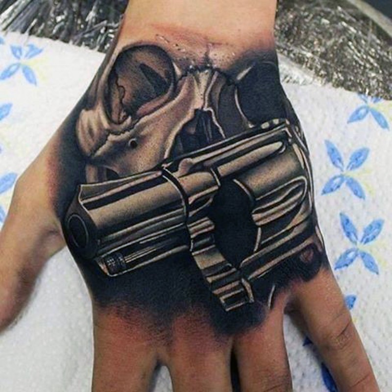 Tatuaje en la mano,  cráneo humano con pistola
