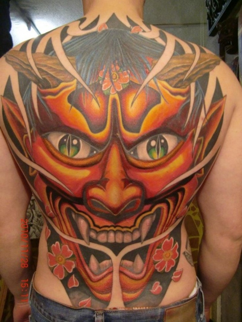 Stunning multicolored whole back tattoo of demonic mask with flowers