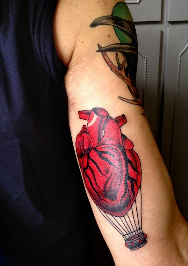 bel dipinto colorato cuore volante come mongolfiere tatuaggio su braccio